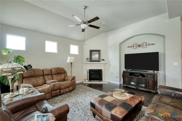 living area featuring dark wood-style floors, ceiling fan, vaulted ceiling, baseboards, and a glass covered fireplace