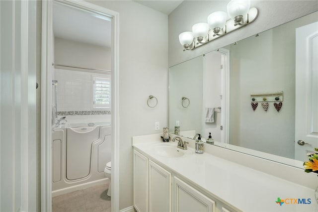 bathroom with toilet, a tub to relax in, and vanity