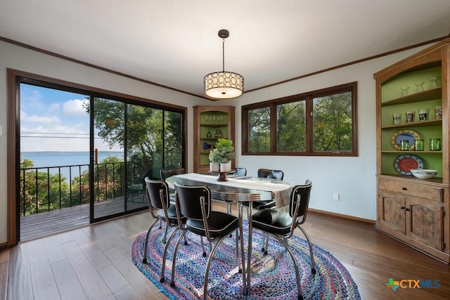 dining space with wood finished floors, a water view, a wealth of natural light, and ornamental molding