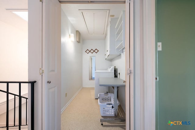 hallway with baseboards, washer / clothes dryer, and attic access