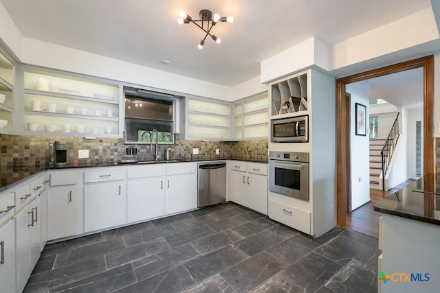 kitchen with dark countertops, open shelves, appliances with stainless steel finishes, and a sink