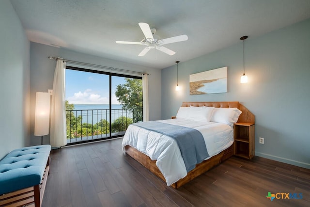 bedroom featuring baseboards, a water view, dark wood finished floors, and access to outside