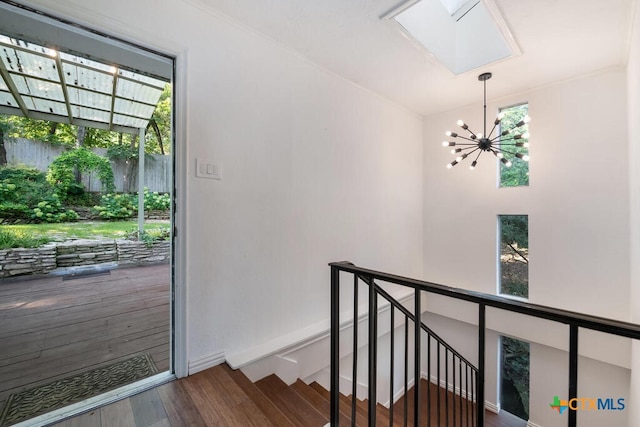 interior space with an upstairs landing, a healthy amount of sunlight, an inviting chandelier, and wood finished floors