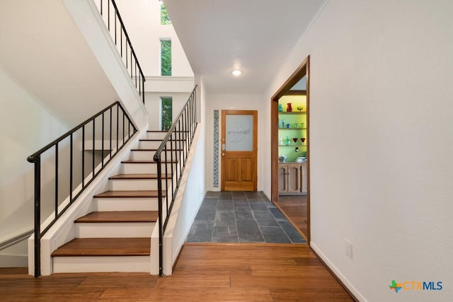 foyer entrance with baseboards, wood finished floors, stairs, and ornamental molding