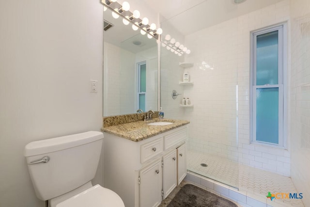 full bathroom featuring vanity, toilet, visible vents, and tiled shower