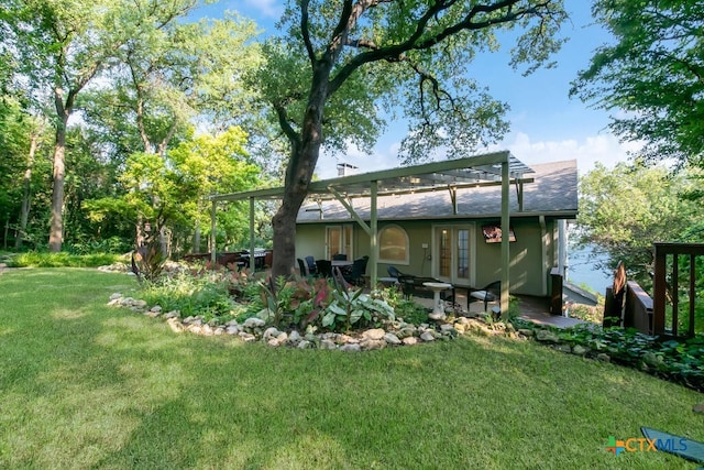 rear view of house with a patio area, a lawn, and roof with shingles