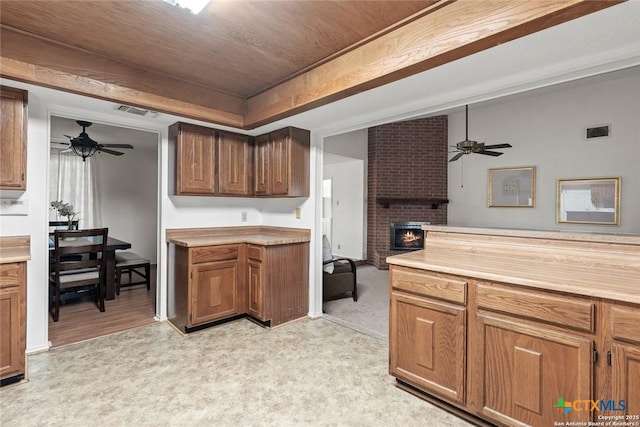 300 Ridge Crest Dr, Seguin, TX 78155 - kitchen featuring ceiling fan, light countertops, a brick fireplace, and brown cabinets