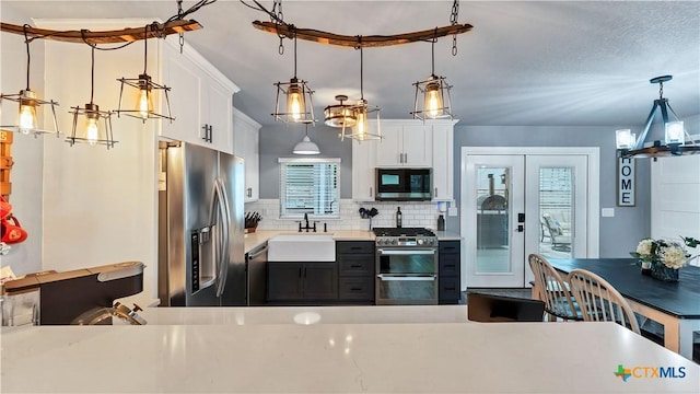 kitchen with stainless steel appliances, a sink, light countertops, and white cabinetry