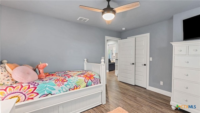 bedroom with ceiling fan, wood finished floors, visible vents, and baseboards