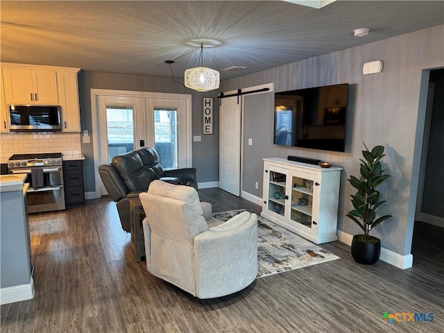 living area featuring dark wood-type flooring, french doors, baseboards, and a barn door