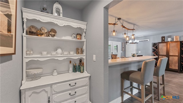 bar featuring white cabinets, pendant lighting, and hardwood / wood-style floors