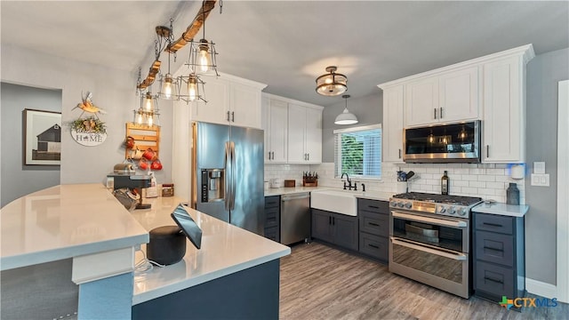 kitchen featuring white cabinets, a peninsula, stainless steel appliances, light countertops, and a sink