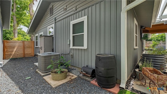 view of side of home featuring central AC, board and batten siding, and fence