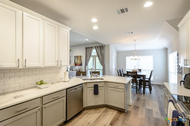 kitchen with stainless steel appliances, a peninsula, a sink, visible vents, and pendant lighting