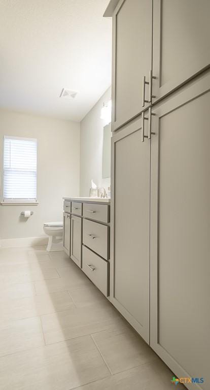 bathroom featuring toilet, visible vents, vanity, and baseboards