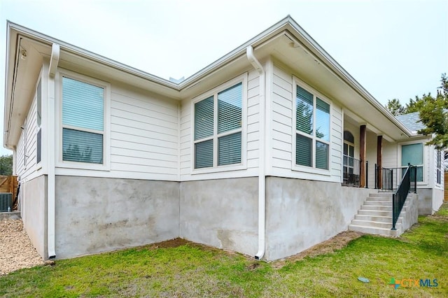 view of property exterior with cooling unit, a lawn, and stairs