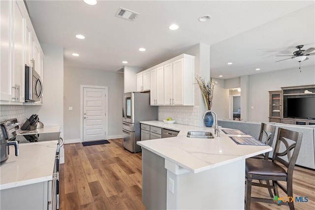 4001 Crockett Ave, Lago Vista, TX 78645 - kitchen featuring a sink, stainless steel appliances, a peninsula, decorative backsplash, and light stone countertops