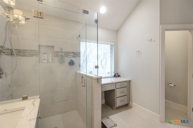 bathroom with lofted ceiling, a shower stall, vanity, and baseboards