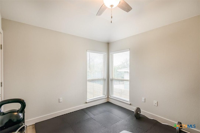 workout room with a ceiling fan and baseboards