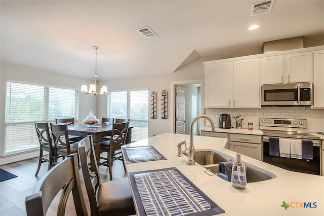 kitchen featuring white cabinetry, visible vents, appliances with stainless steel finishes, and decorative light fixtures