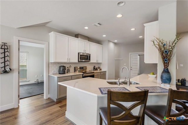 4001 Crockett Ave, Lago Vista, TX 78645 - kitchen with a sink, stainless steel appliances, light wood-type flooring, light countertops, and decorative backsplash
