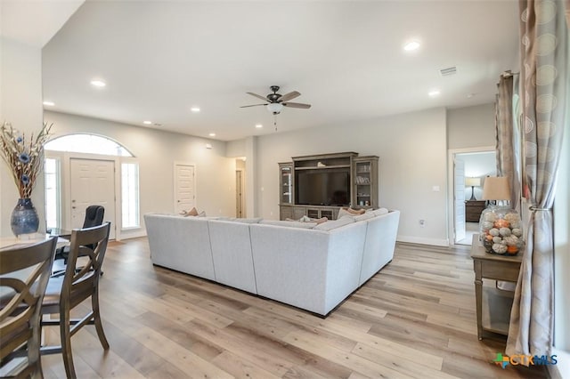 living area with light wood-type flooring, baseboards, a ceiling fan, and recessed lighting