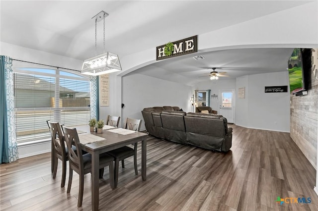 dining space with arched walkways, visible vents, a ceiling fan, and wood finished floors