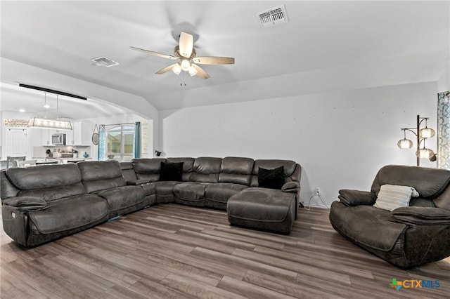 living room with ceiling fan, lofted ceiling, visible vents, and wood finished floors