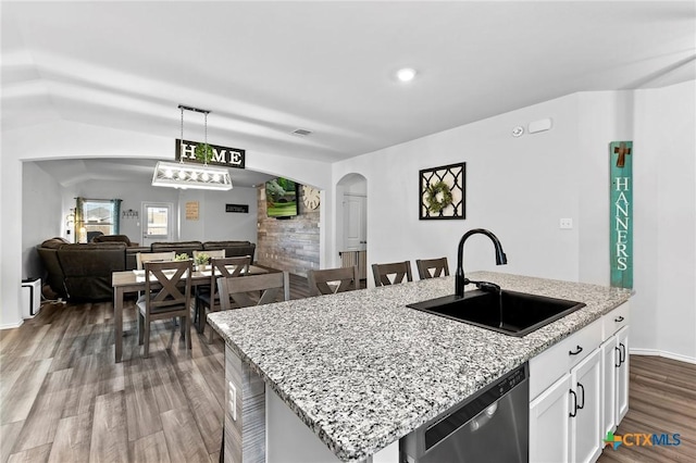 kitchen featuring a sink, open floor plan, dark wood-type flooring, stainless steel dishwasher, and arched walkways