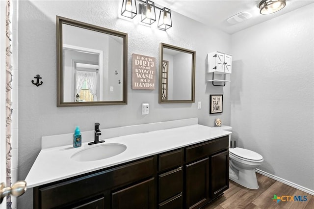 bathroom with toilet, baseboards, visible vents, vanity, and wood finished floors