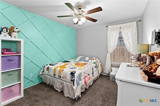 bedroom with dark carpet, ceiling fan, and an accent wall