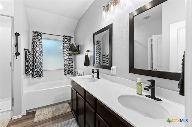 bathroom featuring a garden tub, vaulted ceiling, wood finished floors, and a sink