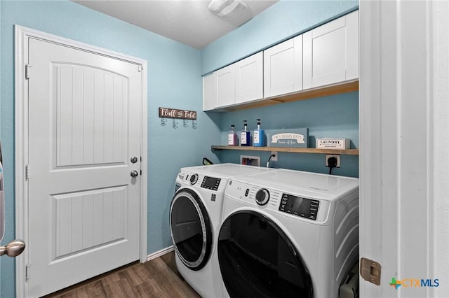 laundry area featuring washing machine and clothes dryer, baseboards, cabinet space, and dark wood-type flooring