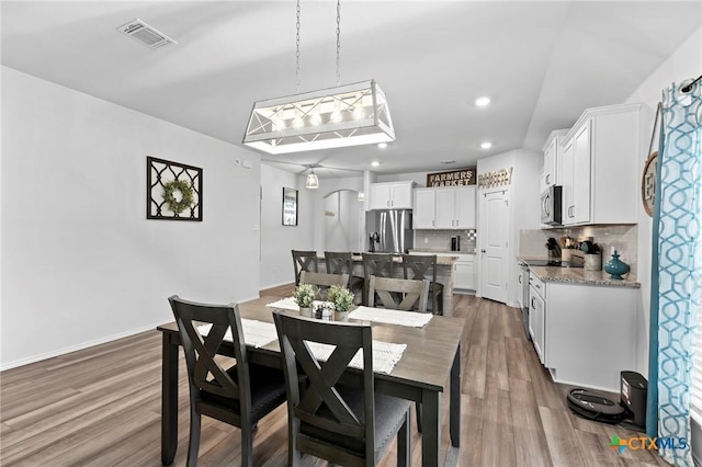 dining space with wood finished floors, visible vents, baseboards, arched walkways, and recessed lighting