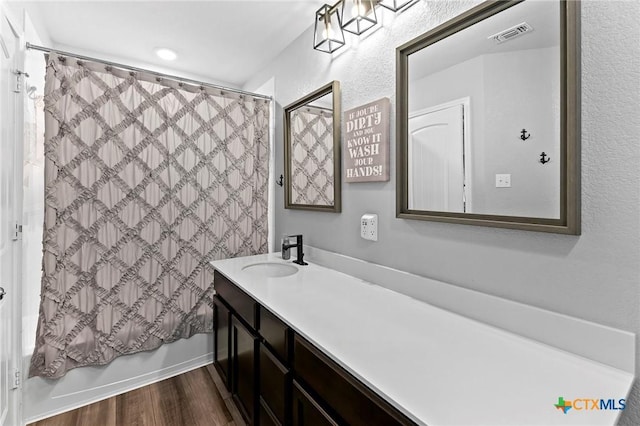 full bathroom with shower / bath combination with curtain, visible vents, wood finished floors, and vanity