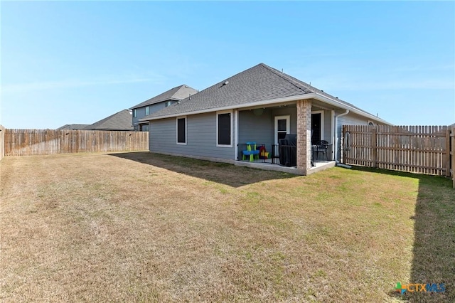 back of property with a lawn, roof with shingles, and a fenced backyard