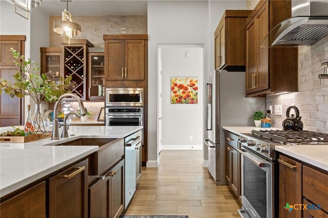 1125 Provence Pl, New Braunfels, TX 78132 - kitchen featuring stainless steel appliances, wall chimney range hood, a sink, light countertops, and backsplash