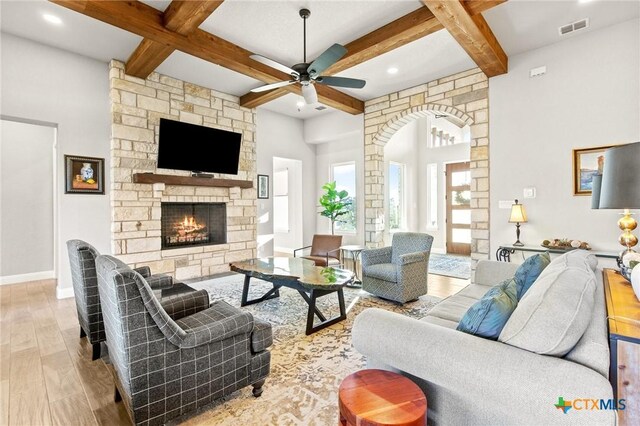 1125 Provence Pl, New Braunfels, TX 78132 - living area featuring wood finished floors, beam ceiling, ceiling fan, a stone fireplace, and arched walkways