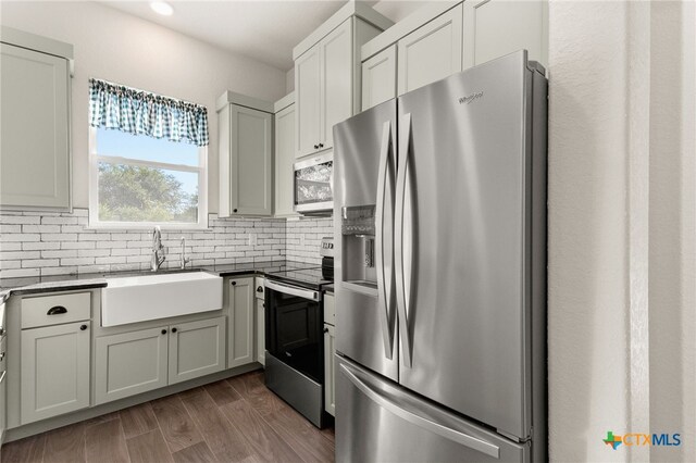 1125 Provence Pl, New Braunfels, TX 78132 - kitchen with stainless steel appliances, a sink, decorative backsplash, dark countertops, and wood finished floors