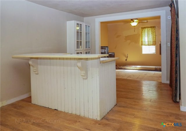 132 Madrona Ln, Bandera, TX 78003 - kitchen featuring light wood-style floors, a breakfast bar area, a ceiling fan, and glass insert cabinets