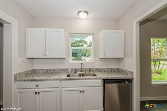 kitchen with stainless steel dishwasher, white cabinetry, sink, and decorative backsplash