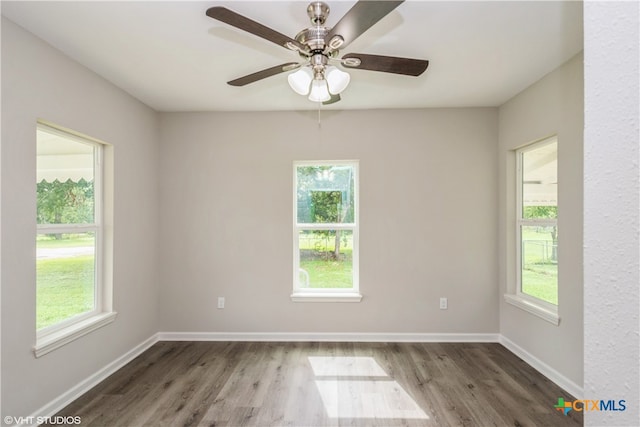 spare room with dark wood-type flooring, a wealth of natural light, and ceiling fan