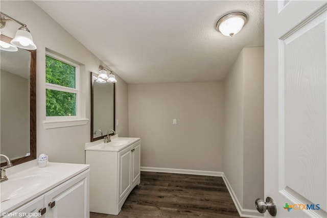 bathroom featuring wood-type flooring, vanity, and a textured ceiling