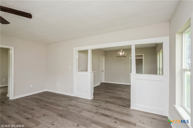 empty room with wood-type flooring, ceiling fan, and a textured ceiling