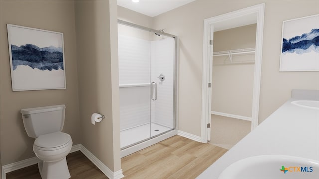 bathroom with hardwood / wood-style flooring, a shower with door, vanity, and toilet