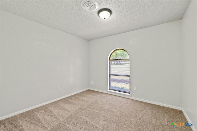 carpeted empty room with a textured ceiling