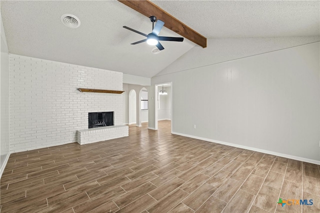 unfurnished living room with lofted ceiling with beams, a fireplace, a textured ceiling, hardwood / wood-style flooring, and ceiling fan