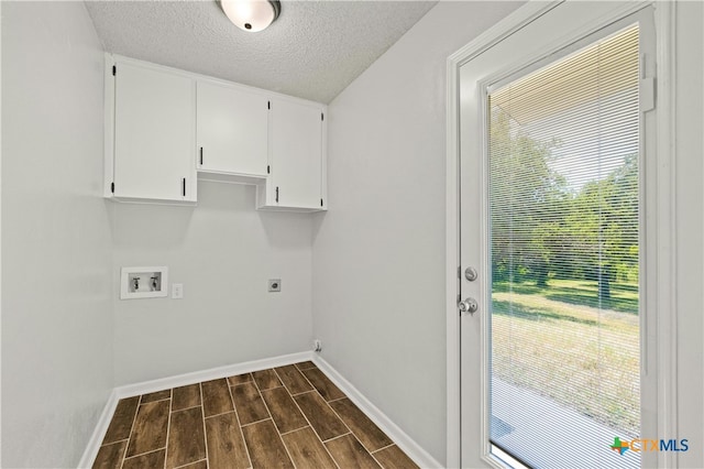 clothes washing area featuring dark wood-type flooring, cabinets, plenty of natural light, and a textured ceiling