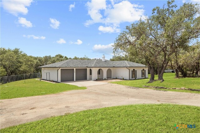 ranch-style house with dirt driveway, a front yard, fence, and an attached garage