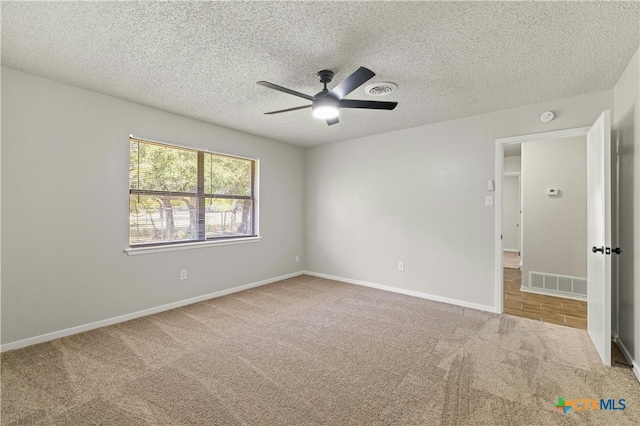 carpeted empty room featuring ceiling fan and a textured ceiling